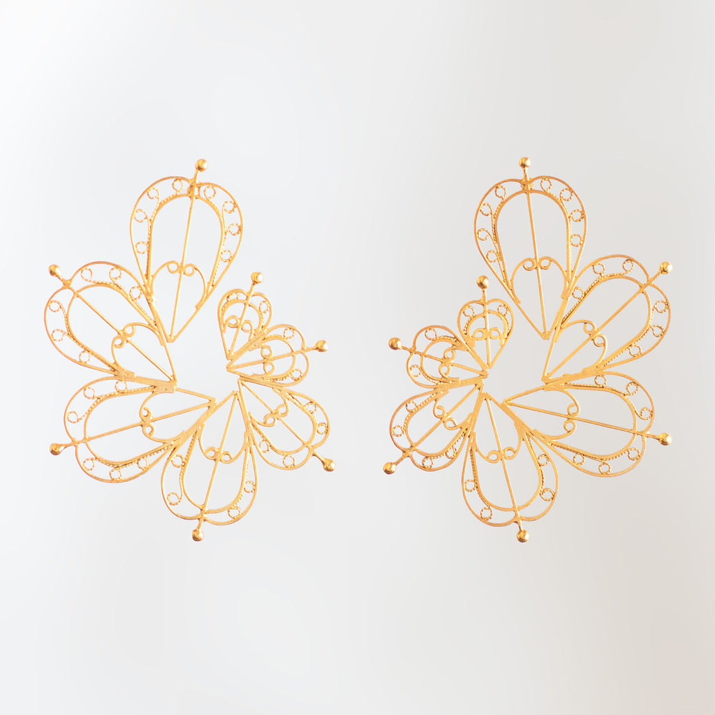 Detalle de tejido artesanal en aretes dorados espiral latido de DAILA.