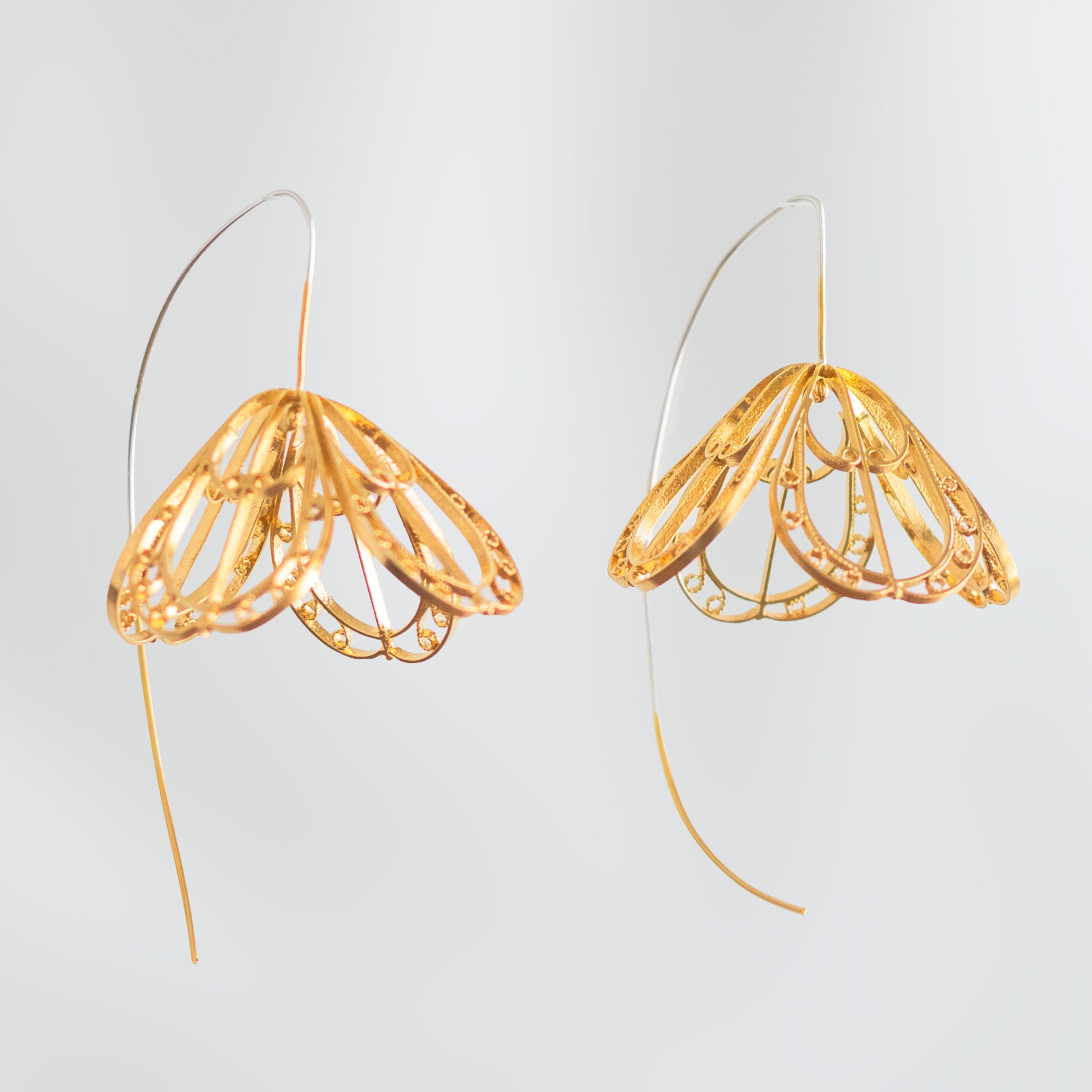 Detalle de los Aretes Gancho Medio Sombrerito, diseño colgante en forma de campana tejido a mano en filigrana de plata con baño de oro.